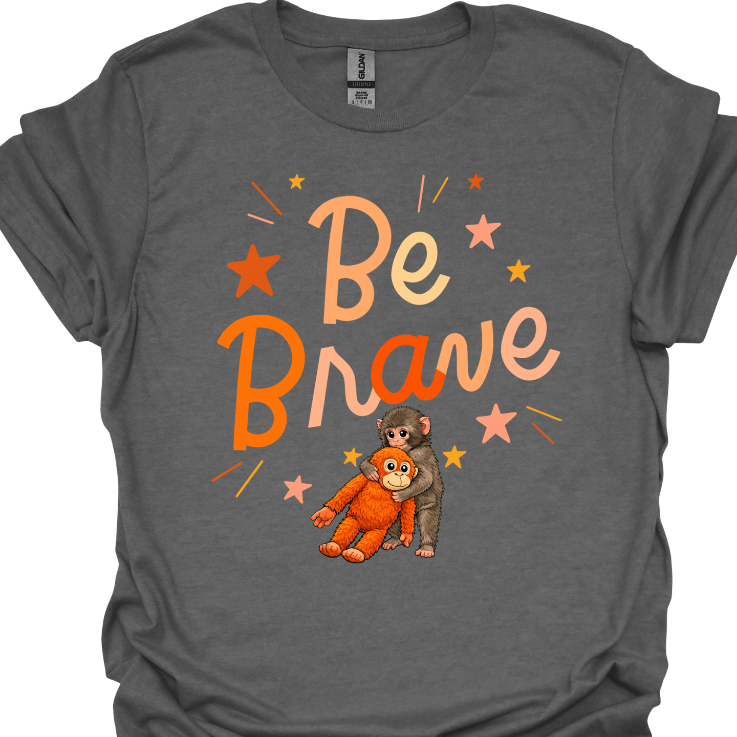 gray t-shirt with the words ‘Be Brave’ and an illustration of a baby monkey hugging an orange plush monkey surrounded by star accents.