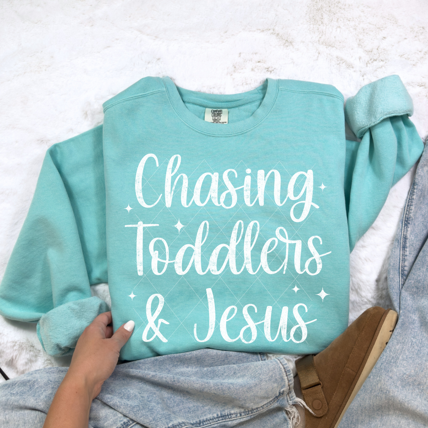 Chasing Toddlers & Jesus sweatshirt in Chalky Mint — flat-lay on cozy backdrop with casual jeans and slippers