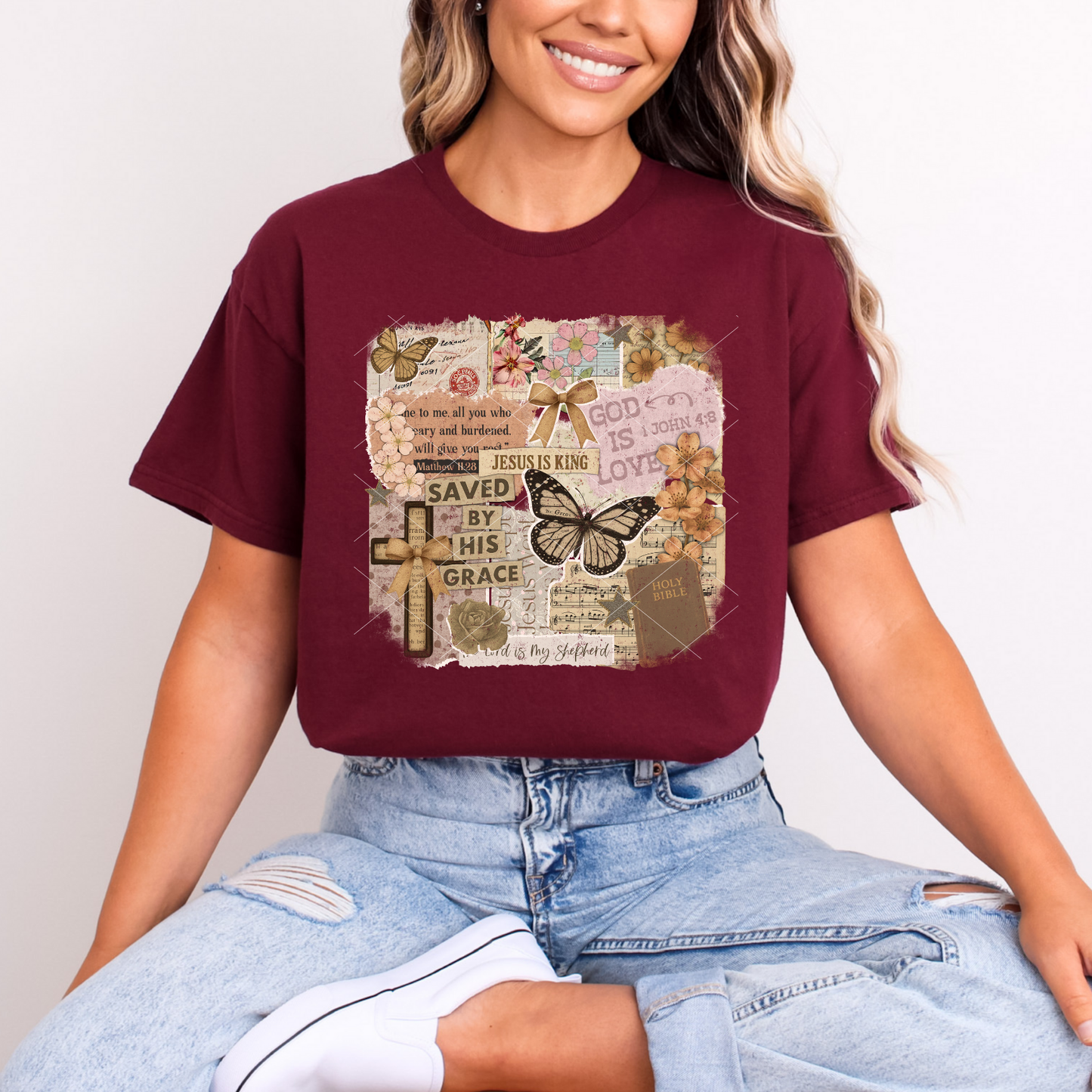 Christian scrapbook-style tee on maroon shirt featuring butterflies, floral accents, crosses, and layered Scripture collage