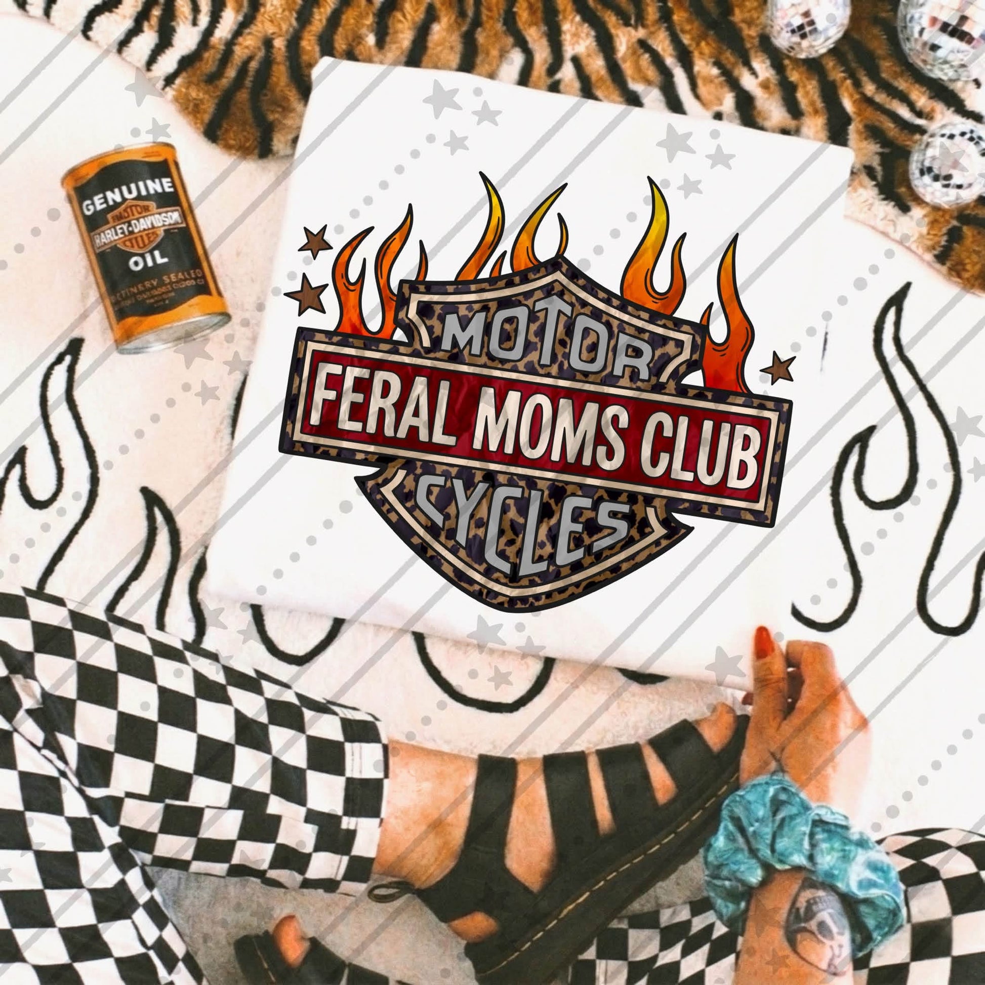 Feral Moms Club graphic design featuring a motorcycle club-style emblem with leopard print details, red banner lettering, and orange flames on a white graphic tee mockup.