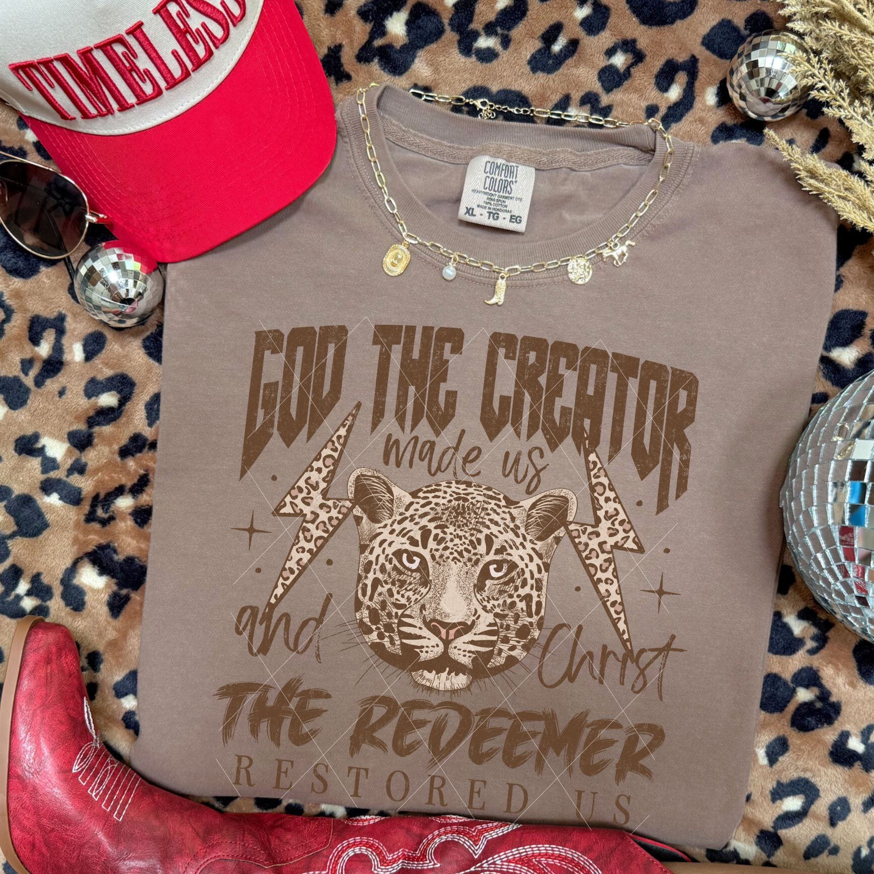 God the Creator Christ the Redeemer tee in Sandstone featuring leopard centerpiece, lightning bolts, and Scripture-inspired text.