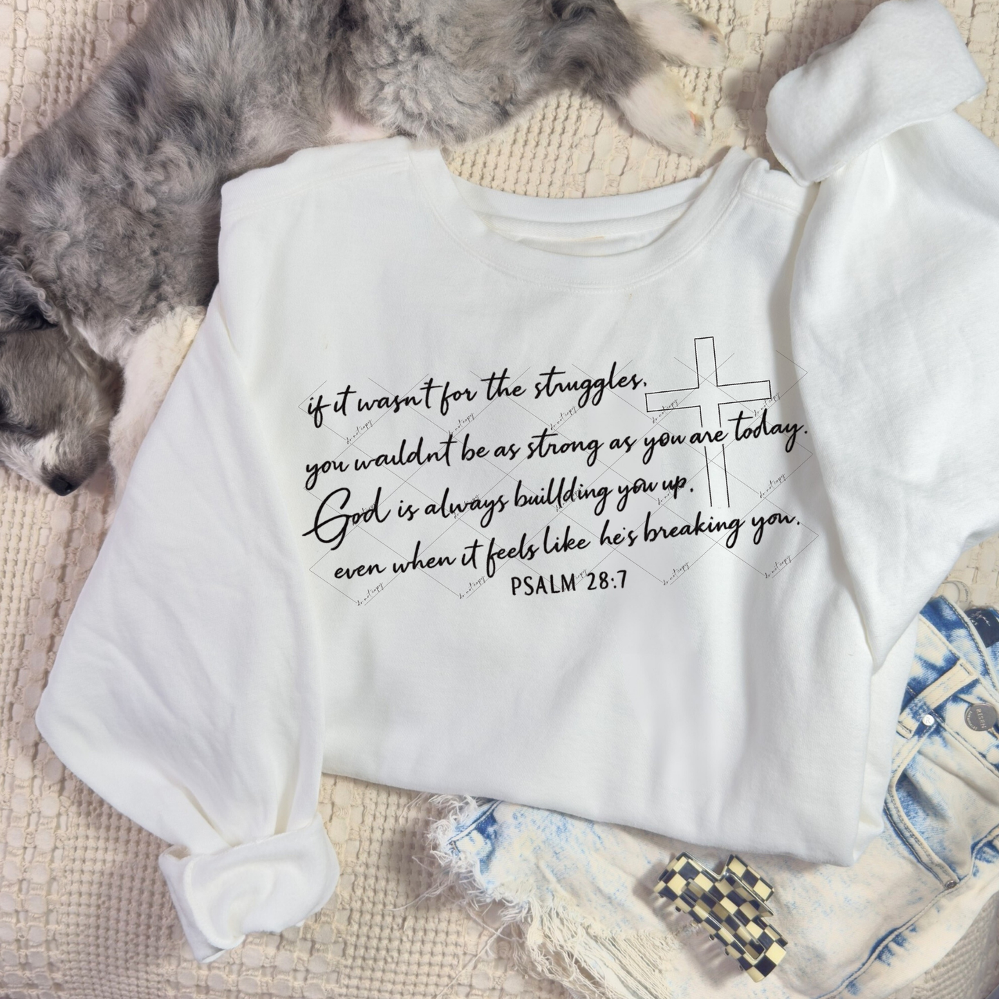 White sweatshirt with Psalm 28:7 handwritten quote and cross outline, styled flat-lay with dog, denim, and cozy accessories.