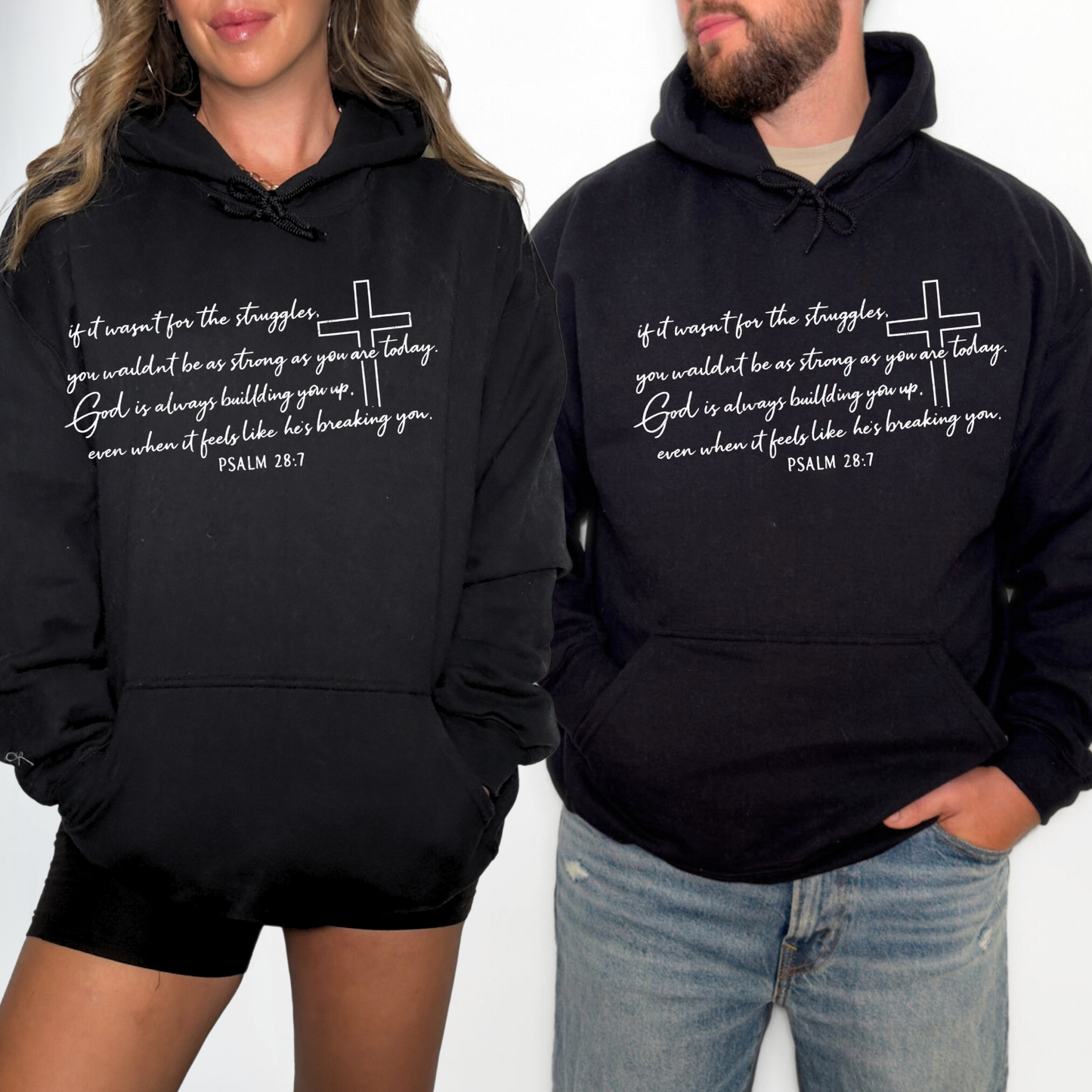 Black unisex hoodie displaying Psalm 28:7 quote in white script with cross sketch, modeled by man and woman.