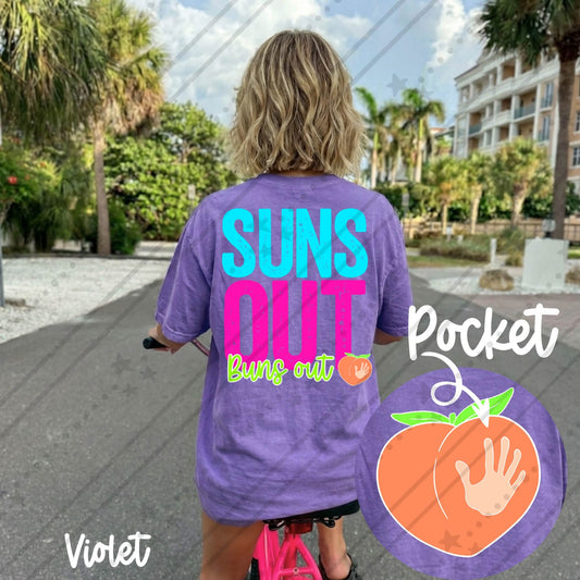 Comfort Colors violet graphic t-shirt featuring a colorful "Suns Out Buns Out" summer design on the back with a matching peach pocket graphic on the front, styled for beach vacations and summer travel.