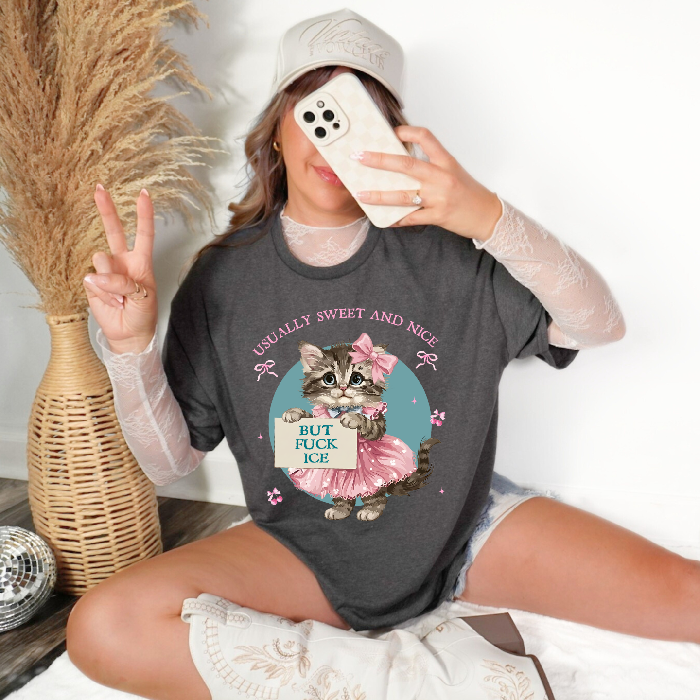 Woman wearing heather dark grey T-shirt featuring retro kitten holding a sign that says, ‘But F*ck ICE’ with text ‘Usually Sweet and Nice,’ styled with layered lace sleeves.