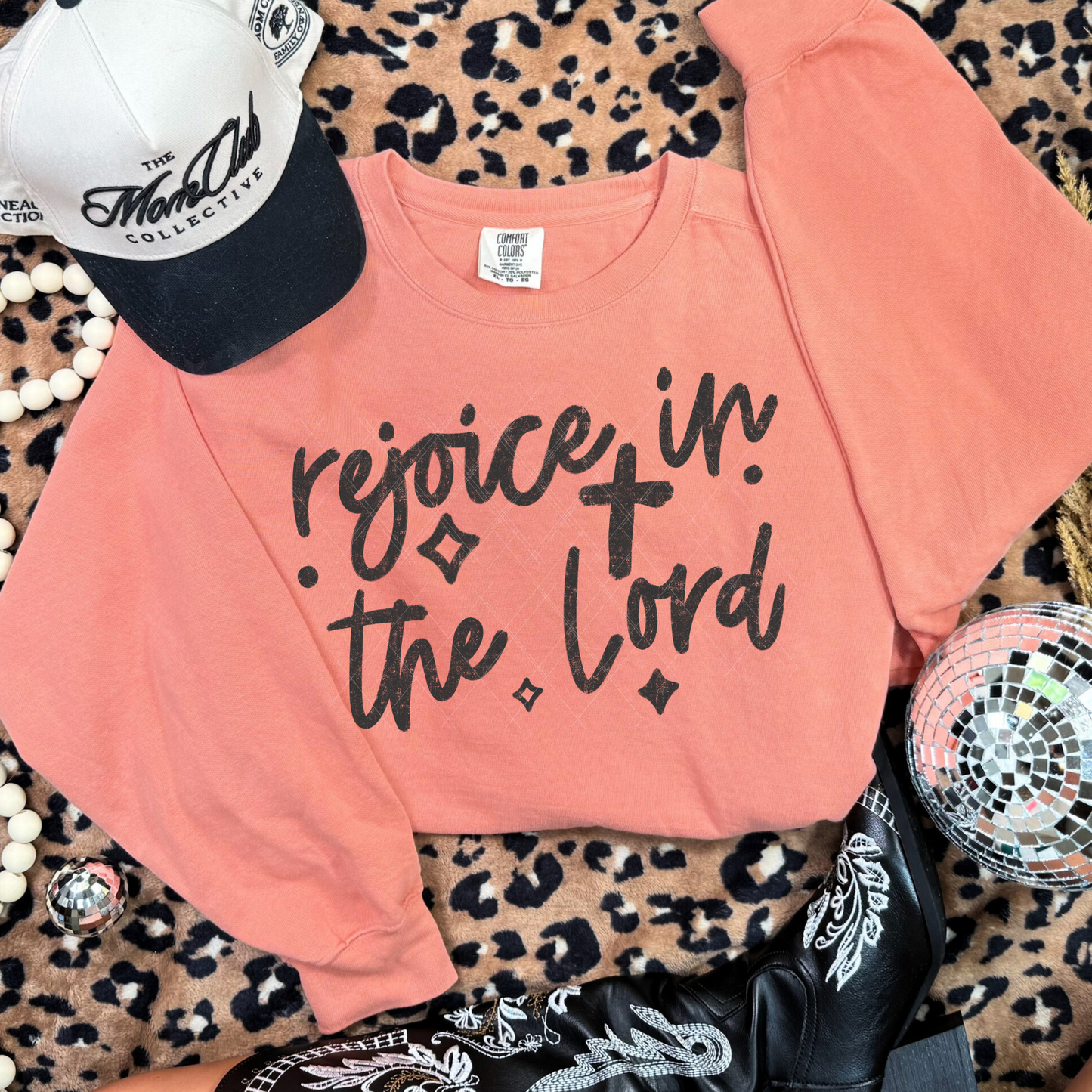 Terracotta Comfort Colors sweatshirt with ‘Rejoice in the Lord’ black hand-lettered design styled with western boots and accessories.”
