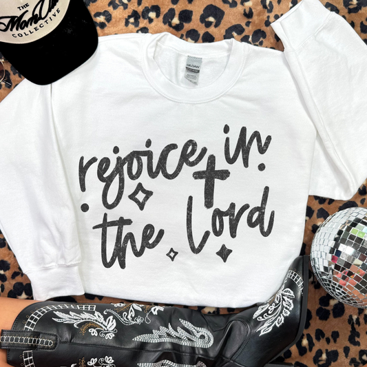 White Gildan sweatshirt with bold black ‘Rejoice in the Lord’ lettering displayed on leopard-print background with western boots.